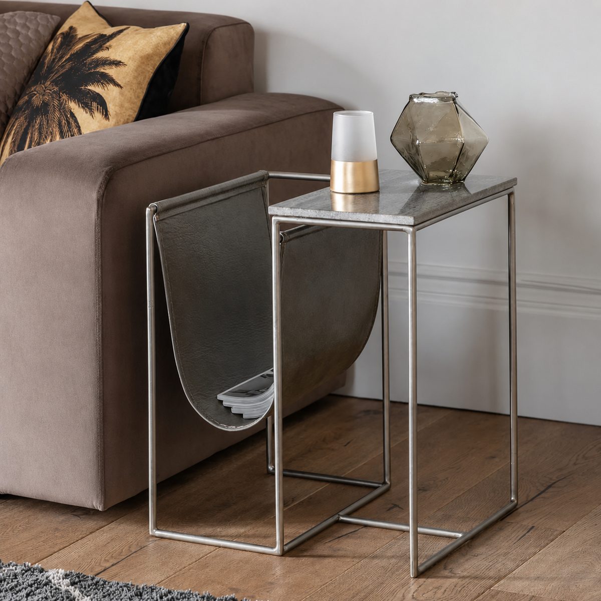 Kildare leather-sling magazine side table — brushed-metal frame with grey stone top, styled beside a sofa